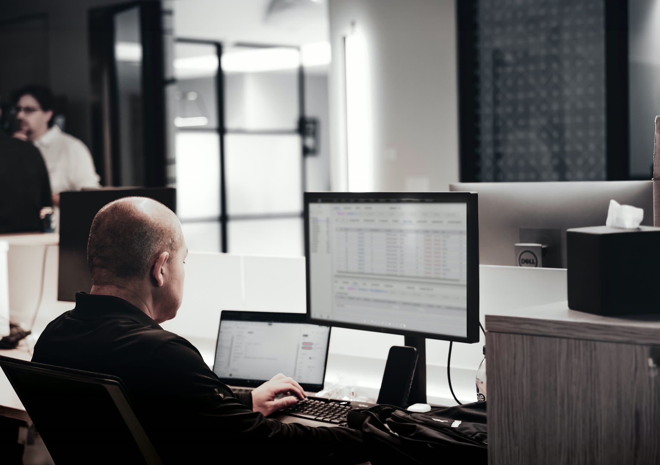 A transportation operator at a desk, working a load board across two screens
